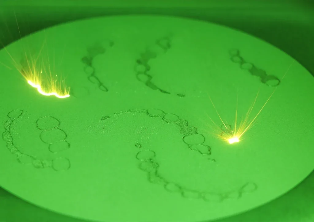 Selective laser melting chamber mid-build, printing a metal part.